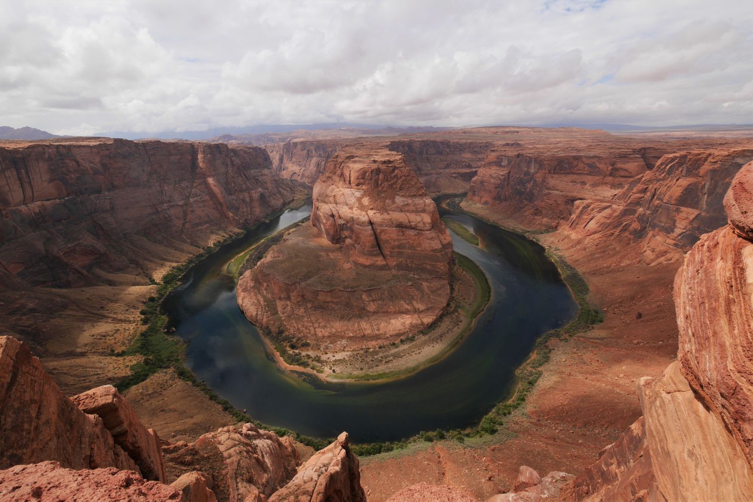 Canyon with river forming a horseshoe bend around a large rock formation.