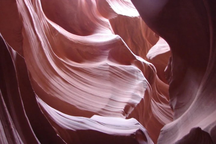 Smooth, swirling red rock formations in a narrow slot canyon.