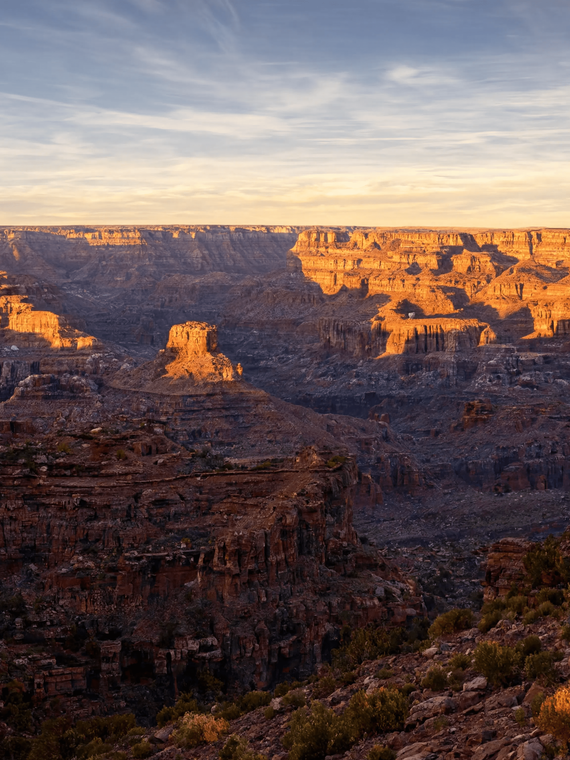 Sunrise over Grand Canyon with dramatic shadows on the rugged landscape.