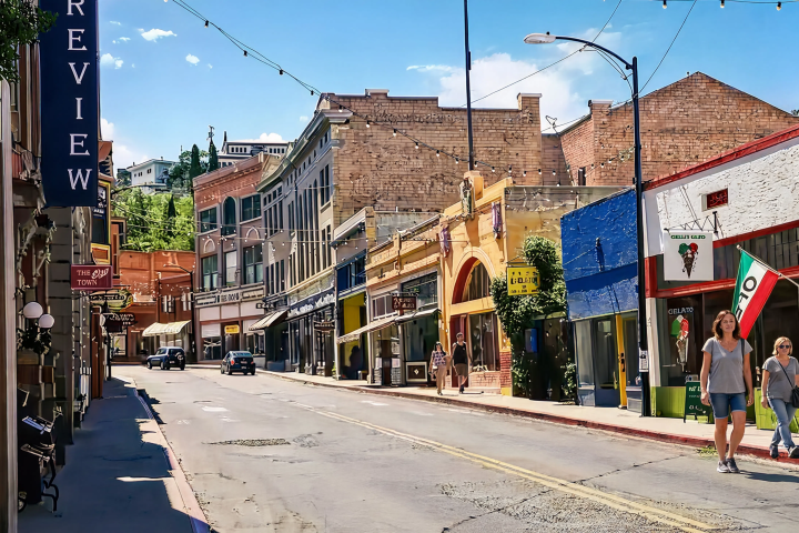 People walk near colorful buildings on a small town street on a sunny day.