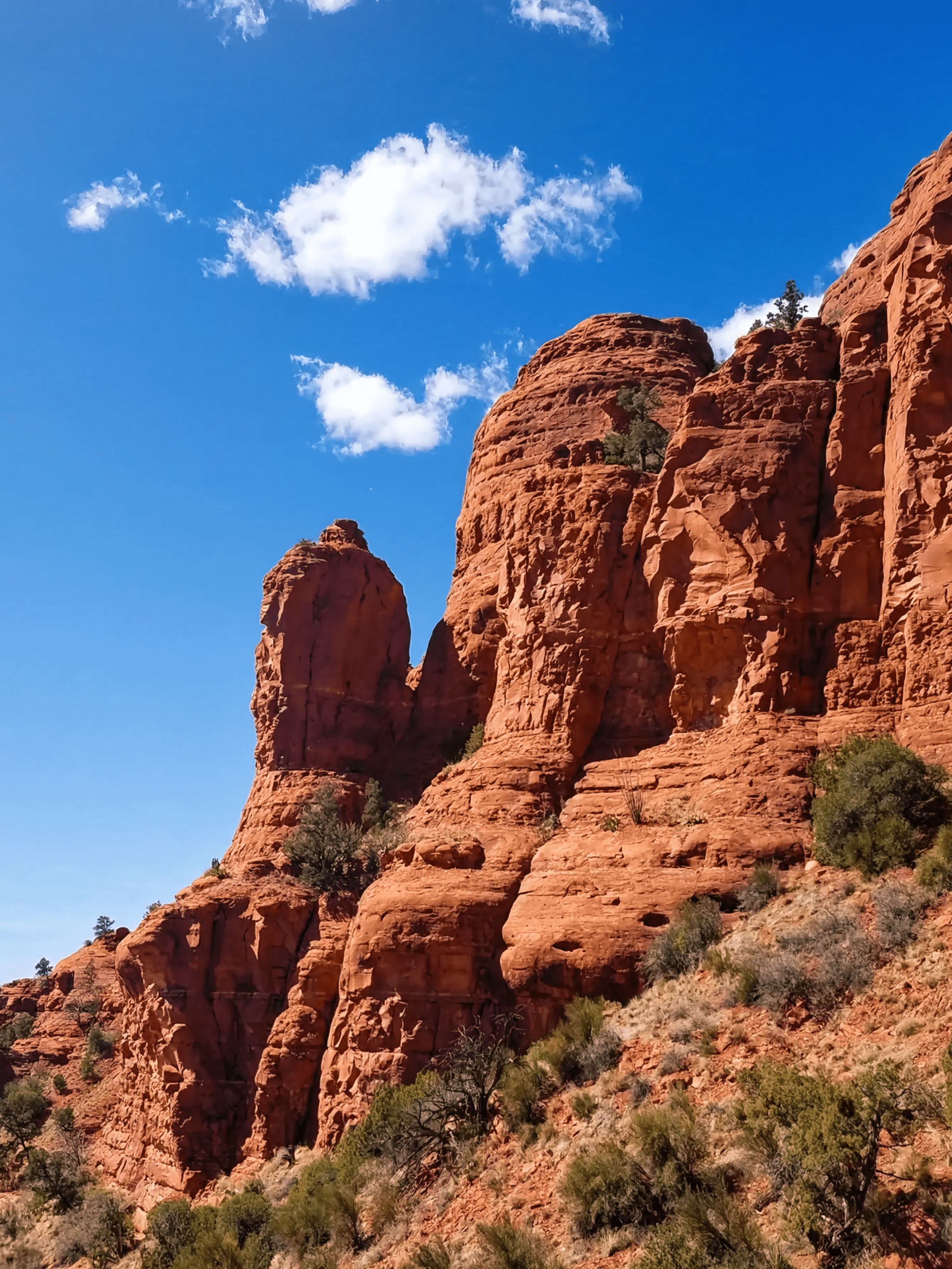 Red rock formations under a clear blue sky with sparse clouds.