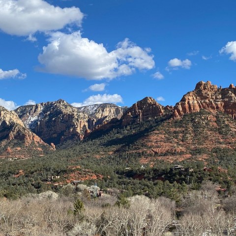 Rocky mountains with snow and clouds under blue sky.