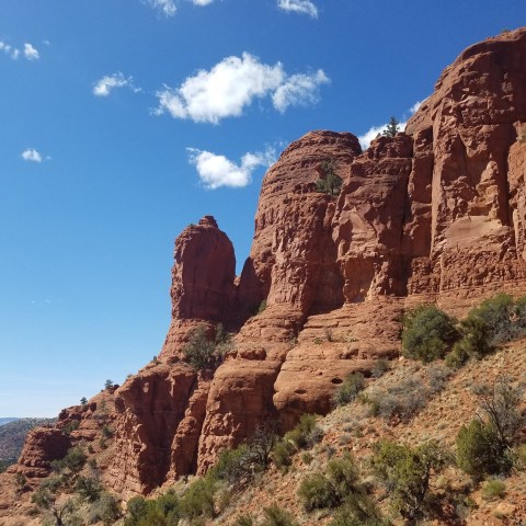 Red rock formations under a blue sky with scattered clouds.