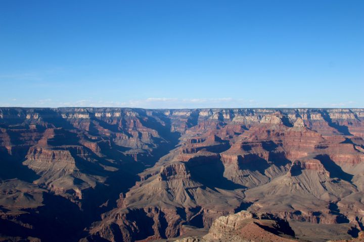 Grand Canyon view with clear blue sky and layered rock formations.